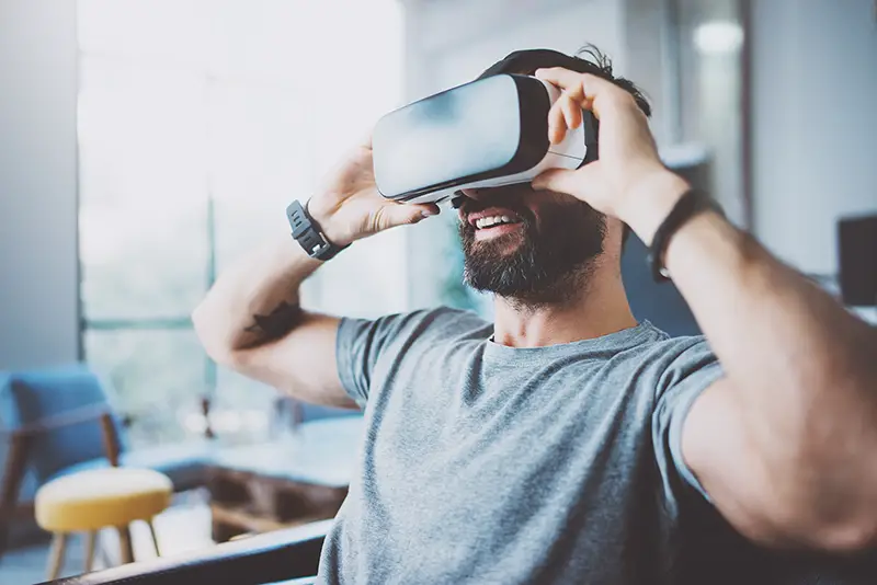Bearded man wearing virtual reality goggles in modern coworking studio