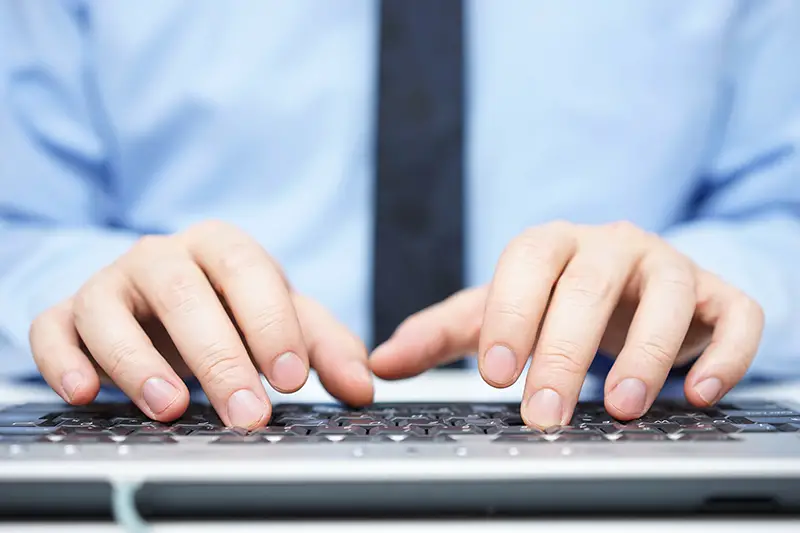 Businessman in blue shirt typing on computer keyboard