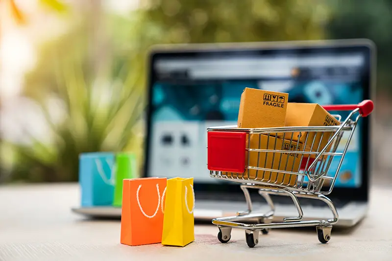 Product package boxes in cart with shopping bag and laptop computer