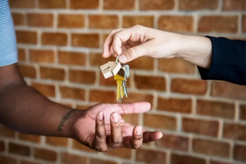 Real estate agent handing the house key to a person