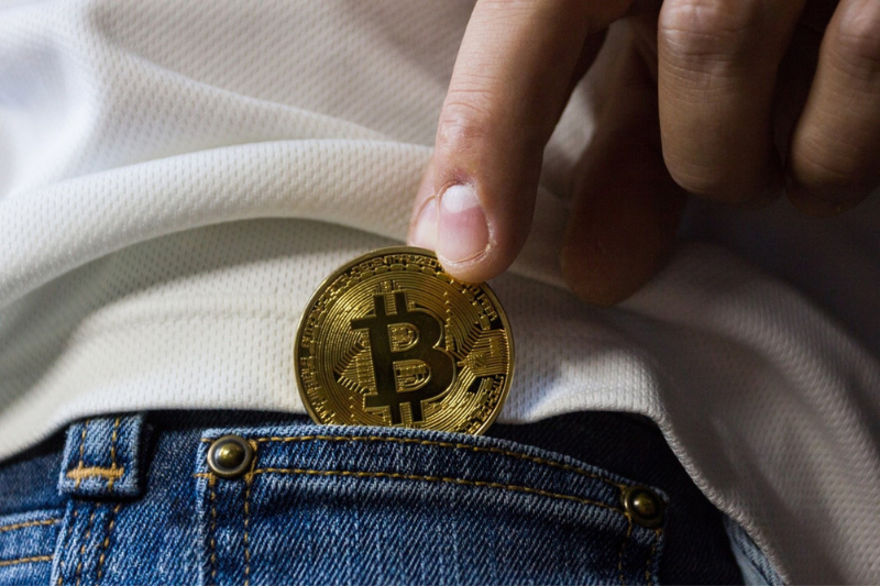 Person putting bitcoin on his pocket