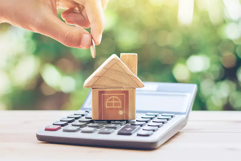 Wood toy house placed on the top of calculator