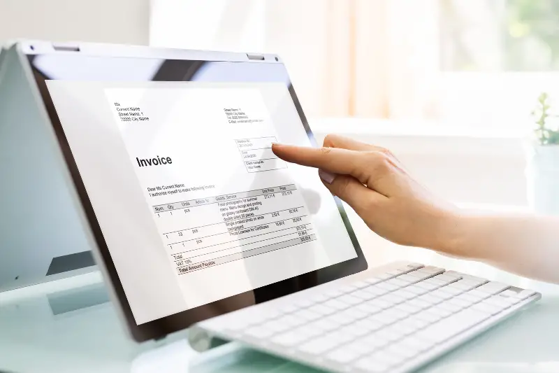 Person working on invoices on laptop computer