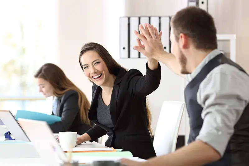 Two happy coworkers celebrating success giving five at office