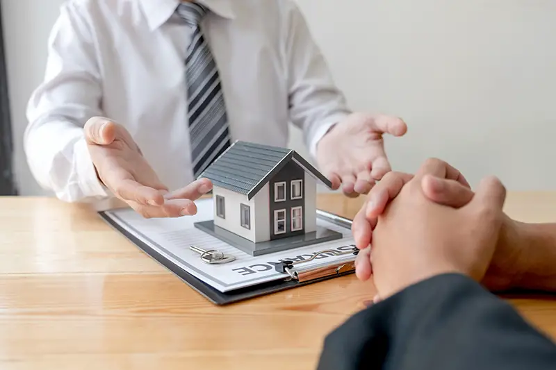 A real estate agent with House model is talking to clients