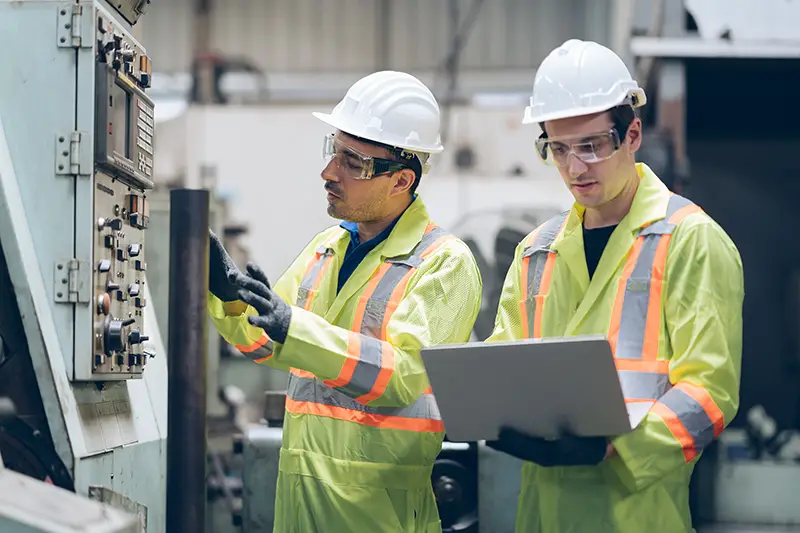 technician engineer and mentor checking process on laptop to automated CNC in factory