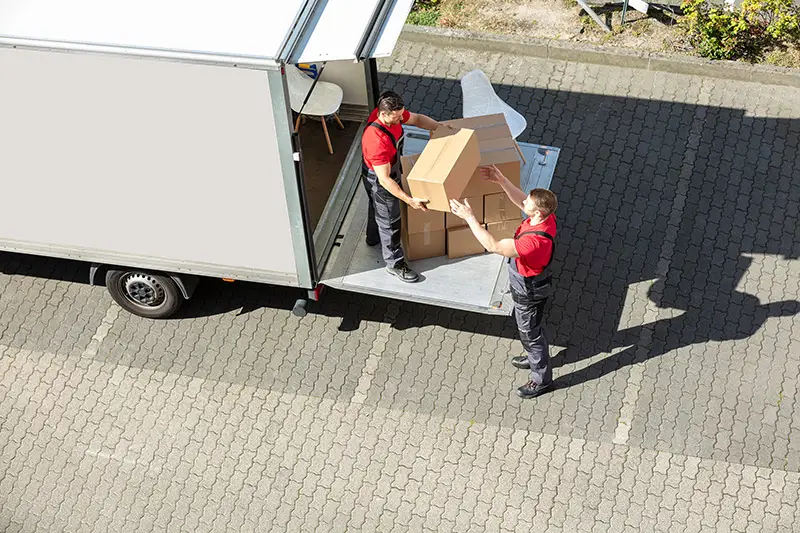 An Overhead View Of A Male Movers Unloading The Cardboard Boxes Form Truck