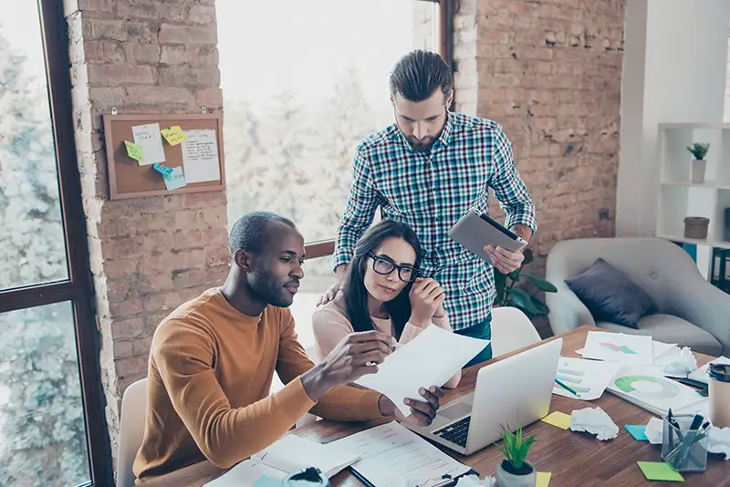 Team of three people working in front of laptop