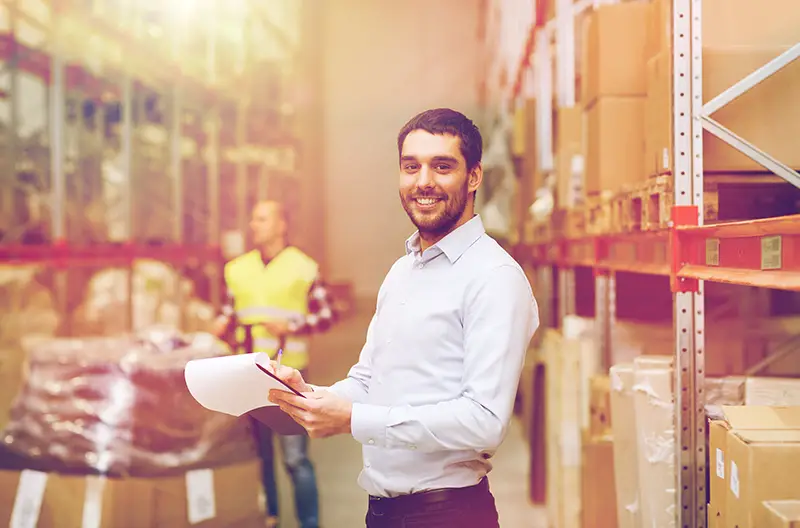 happy businessman or supervisor with clipboards at warehouse