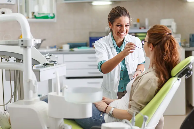 Female dentist in dental office talking with female patient