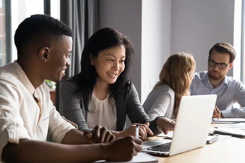 Multi-ethnic affiliates working on task together seated at desk in co-working