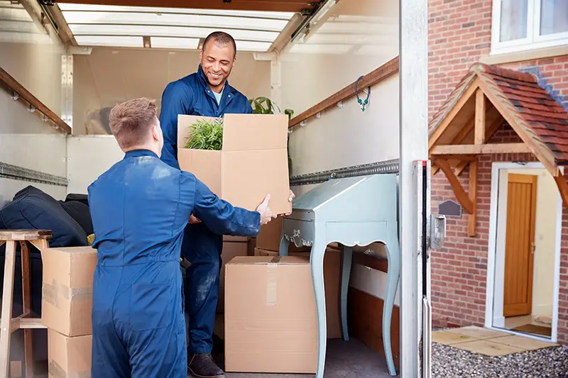 Removal Company Workers Unloading Furniture And Boxes From Truck