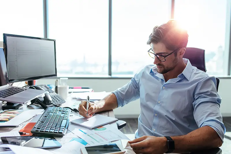 Entrepreneur writing notes sitting at his desk