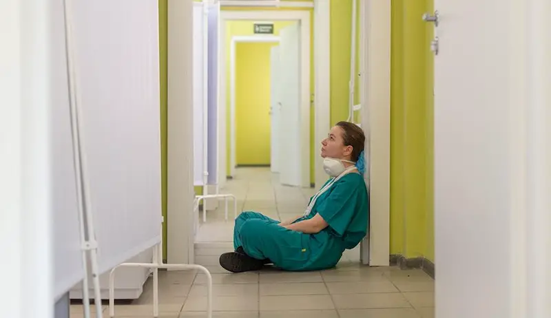 Stressed nurse sitting in the floor