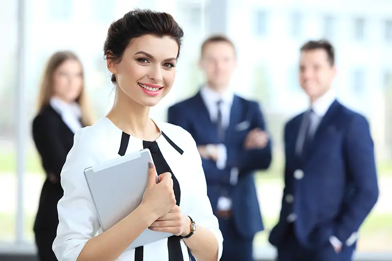 Business woman standing in foreground with a tablet in her hands