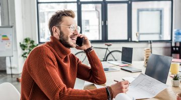 Young businessman talking on the phone while sitting in his desk