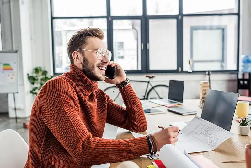 Young businessman talking on the phone while sitting in his desk