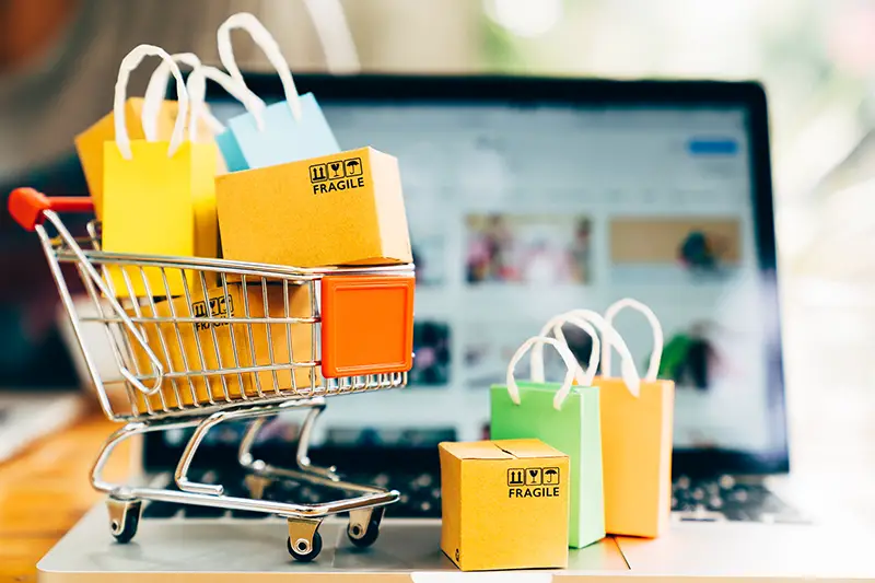 Product package boxes and shopping bag in cart with laptop computer