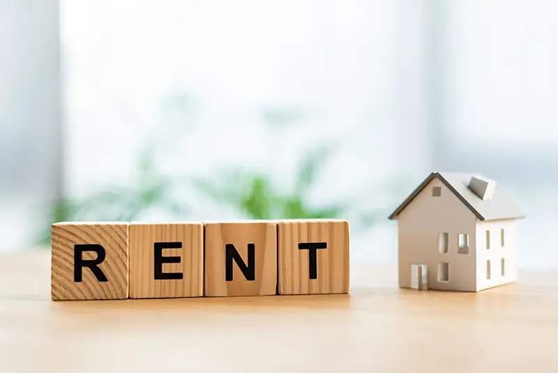 Cardboard house near wooden cubes with rent lettering