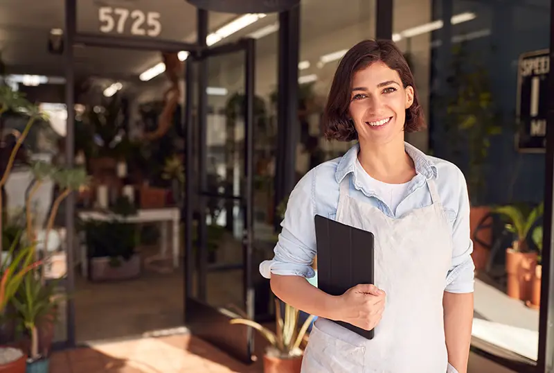 Female Owner Of Florists With Digital Tablet Standing In Doorway