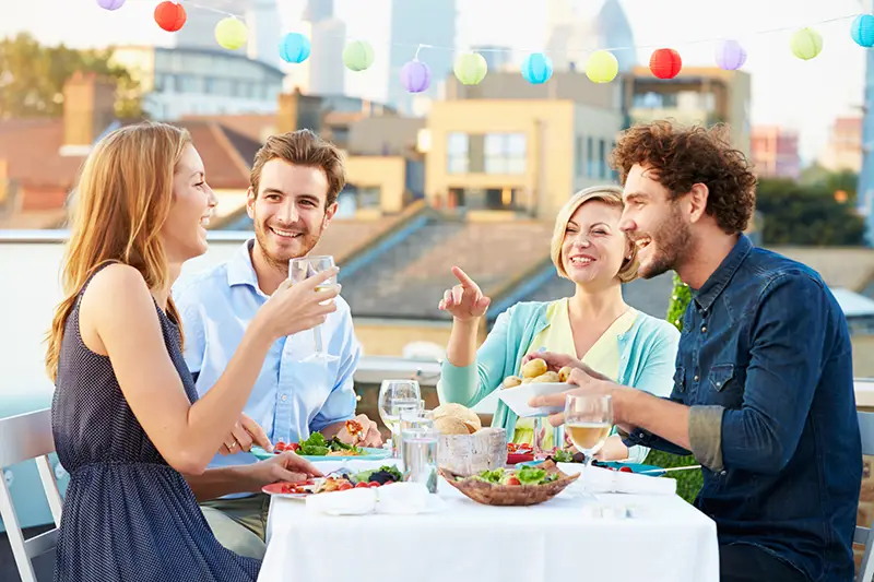 Group Of Friends Eating Meal On Rooftop Terrace