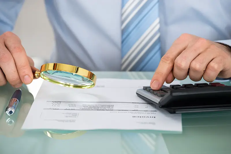 Businesswoman Checking Invoice With Magnifying Glass