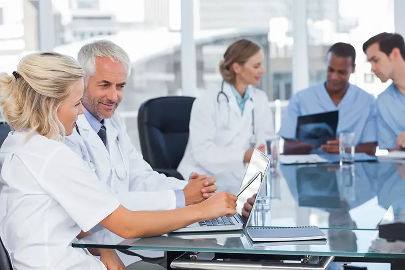 Two smiling doctors using laptop