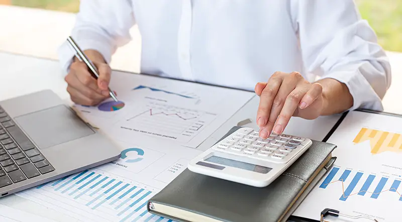 Person using calculator and laptop while working