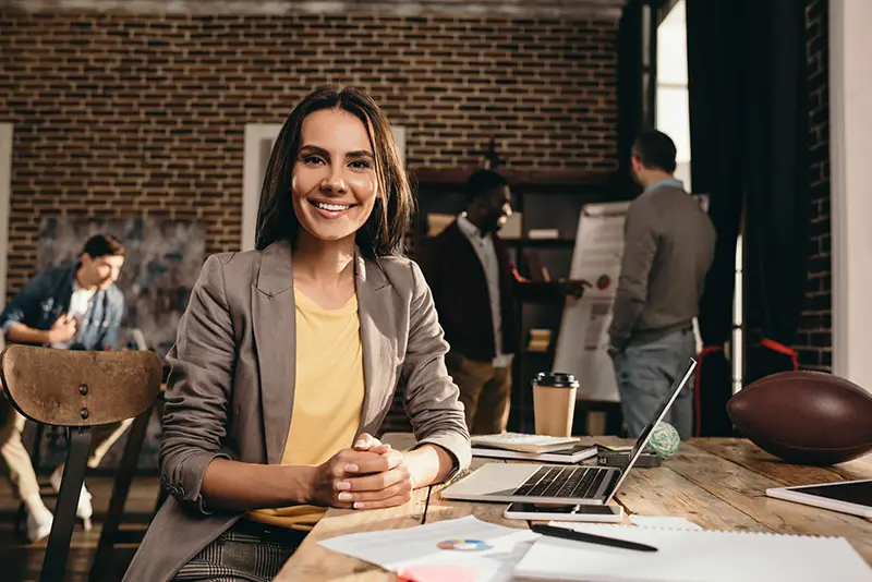 Smiling business woman sitting at desk with laptop