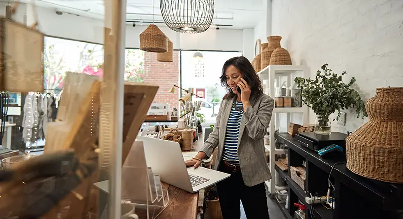 Smiling young Asian woman standing behind a counter in her stylish boutique