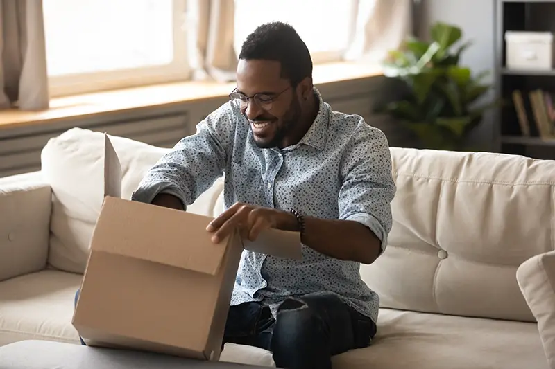 happy ethnic male consumer unpack parcel receive retail purchase