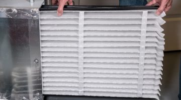 man changing a folded air filter in the HVAC furnace system