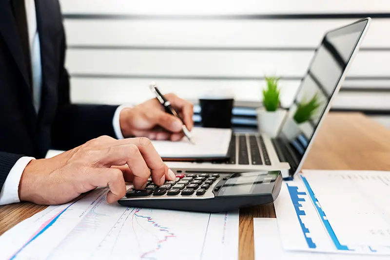 Businessman using calculator and laptop on his work