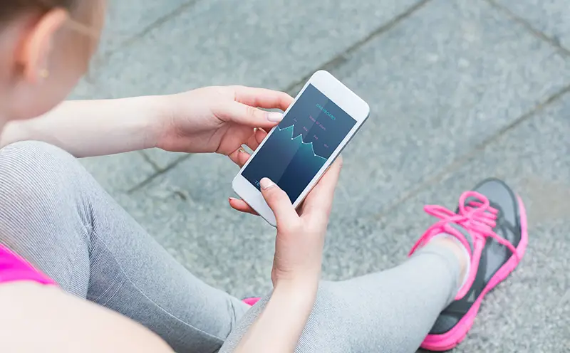 Athletic lady in uniform and sneakers use smartphone to check activity on screen during rest