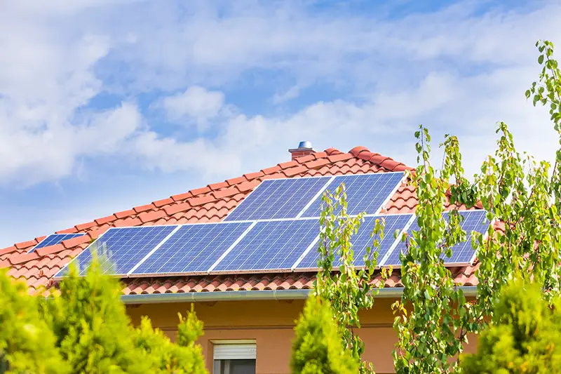 Solar panel cells on the roof of a new house against blue sky.