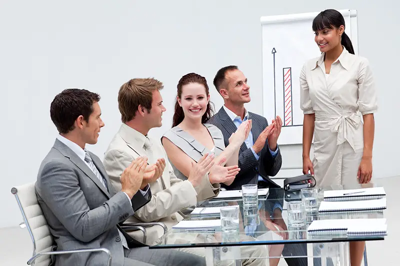 Smiling businesswoman applauding a colleague after giving a presentation