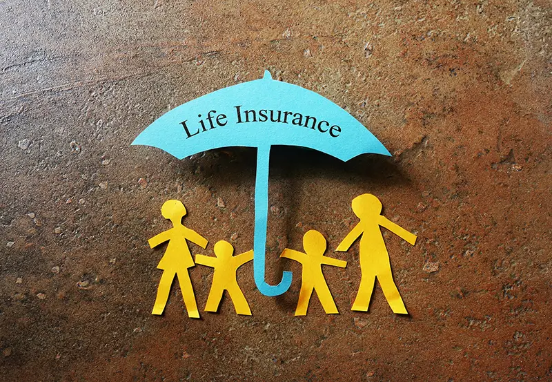 Paper family of four under a Life Insurance paper cutout umbrella