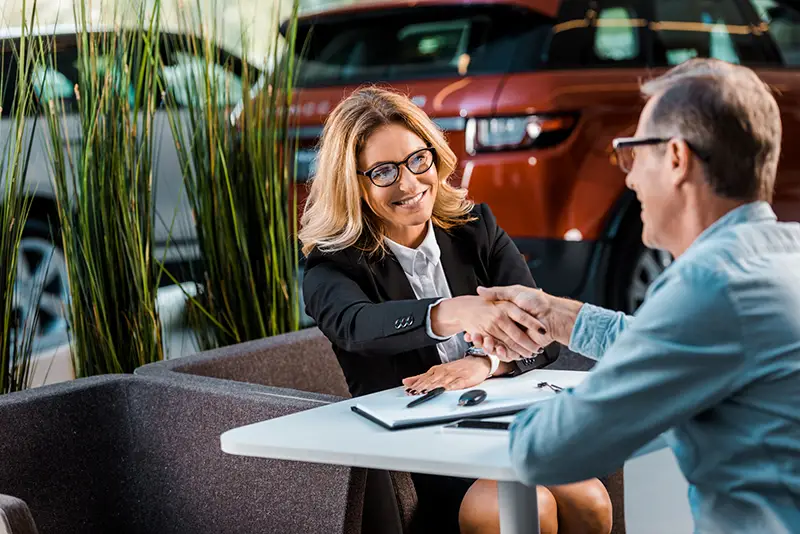 Female car delaer shaking hands with the male customer