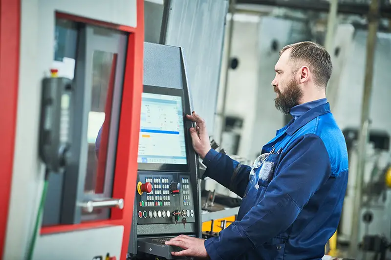 Industrial worker operating cnc machine at metal machining industry