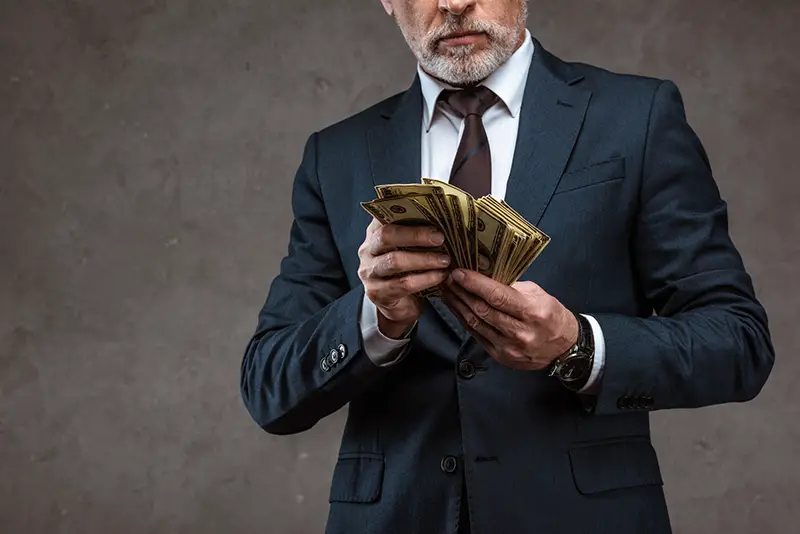 Cropped view of businessman in suit holding dollars