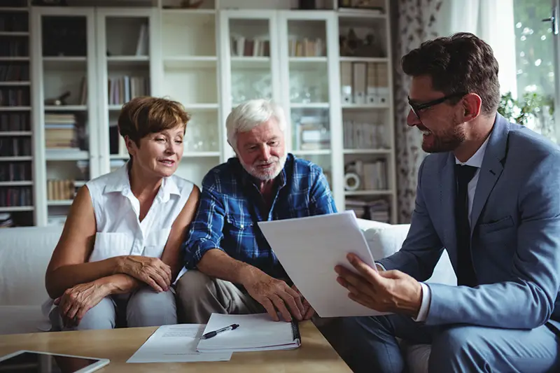 Senior couple planning their investments with financial advisor in living room