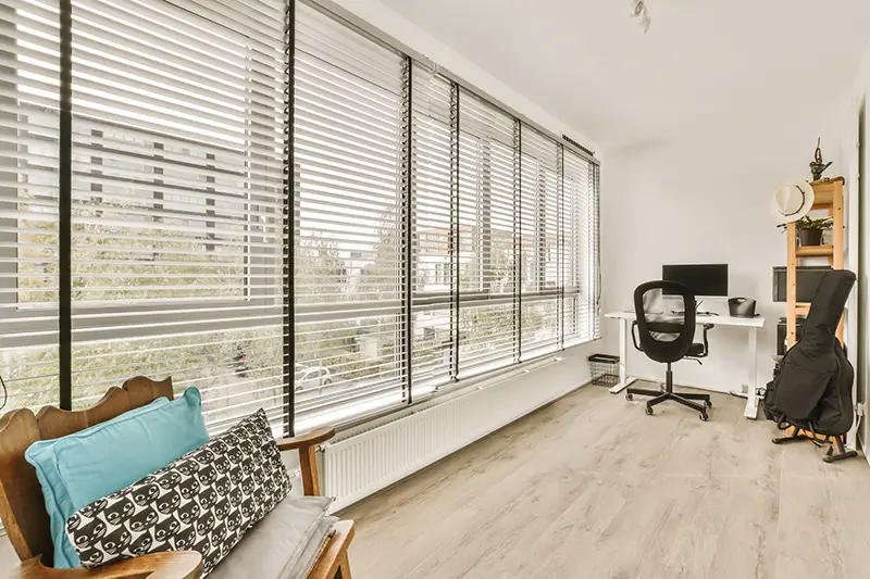 a living room with wood flooring and white shutters on the windows