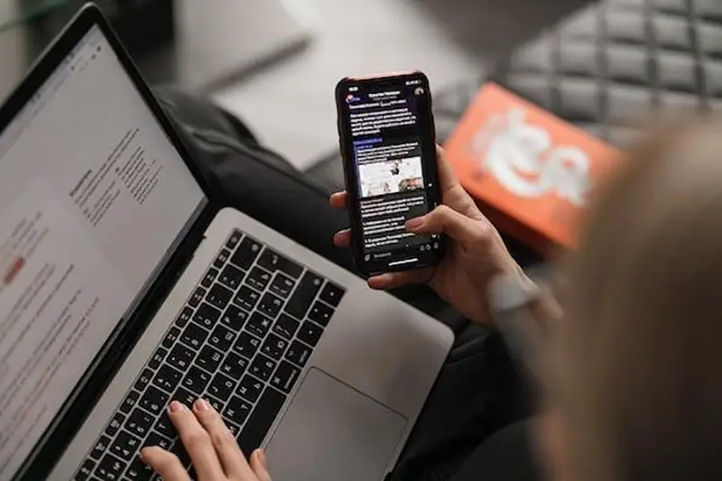 Woman using laptop and black smartphone