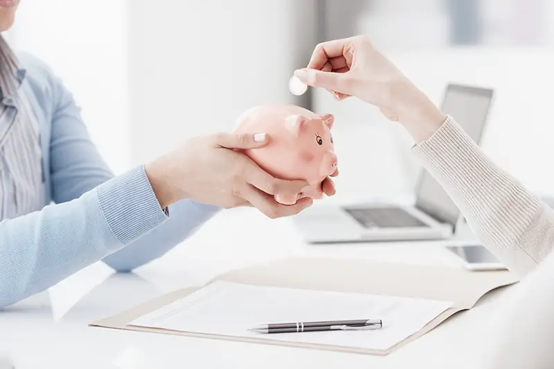 Financial advisor holding a piggy bank and customer inserting a coin