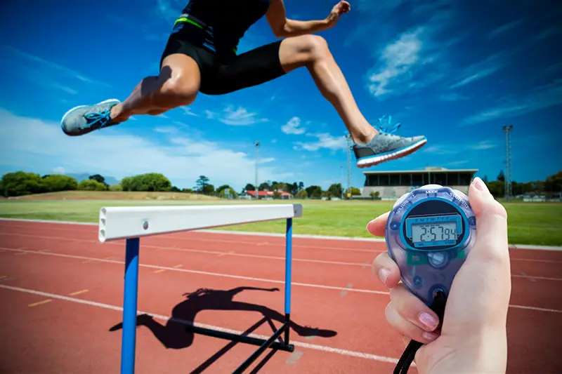 Composite image of a woman holding a chronometer to measure performance against athletic woman doing show jumping