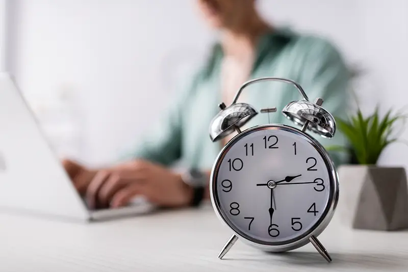 Selective focus of alarm clock on table