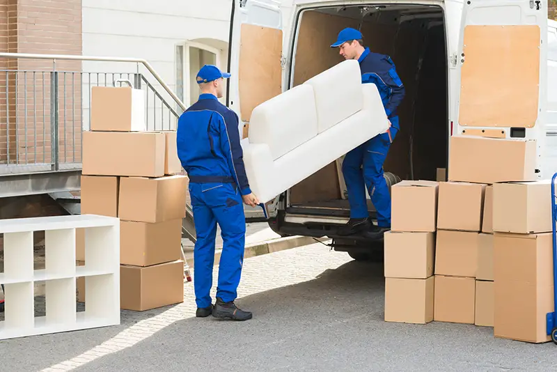 Young male movers unloading sofa from truck on street