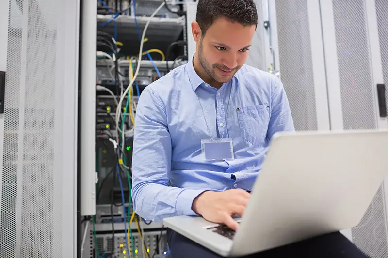 Man using laptop to check servers in data center