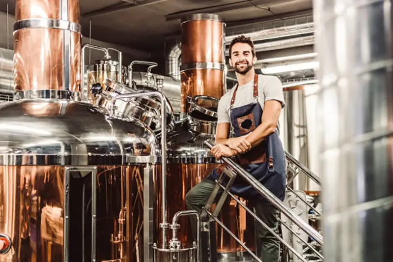 Man standing near brewery metal barrel