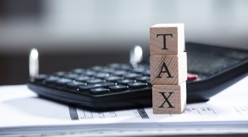 Close-up Of Bill With Calculator And Tax Text On Wooden Blocks